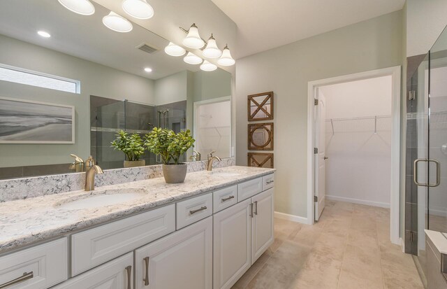 bathroom featuring double vanity, visible vents, a spacious closet, a stall shower, and a sink