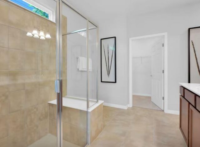 full bath featuring a stall shower, baseboards, a walk in closet, and vanity