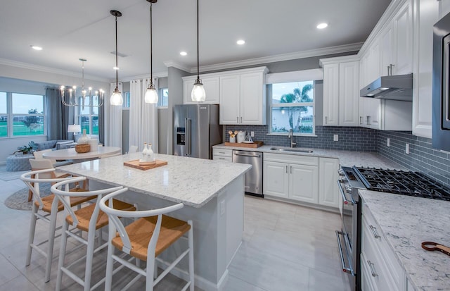 kitchen featuring a breakfast bar area, under cabinet range hood, stainless steel appliances, a sink, and white cabinets