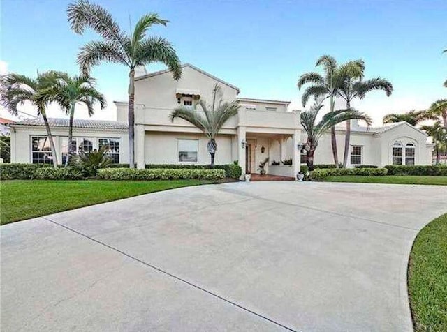 mediterranean / spanish-style house featuring driveway, a front lawn, and stucco siding