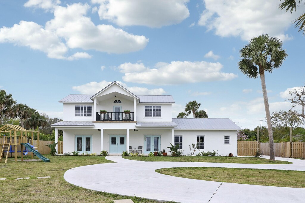 view of front of house with french doors, stucco siding, a standing seam roof, metal roof, and a balcony