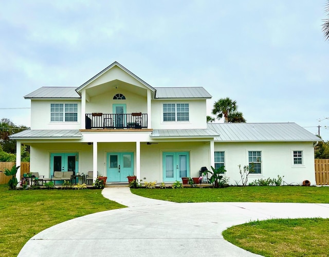 view of front of house with french doors, stucco siding, a standing seam roof, metal roof, and a balcony