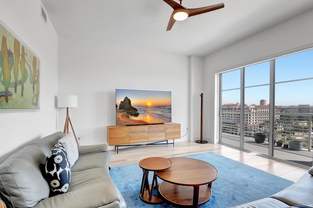 living area with wood finished floors, visible vents, and a ceiling fan