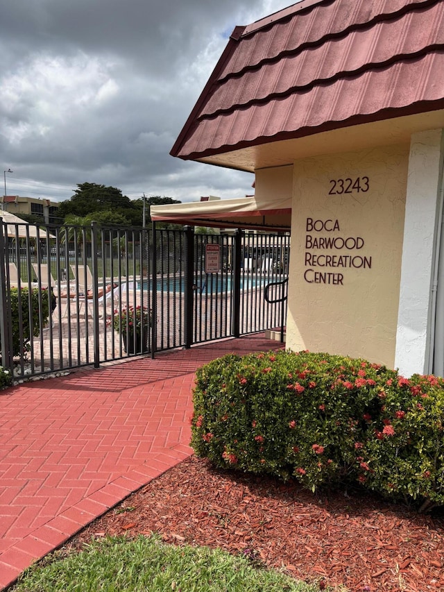 view of gate featuring fence and a community pool