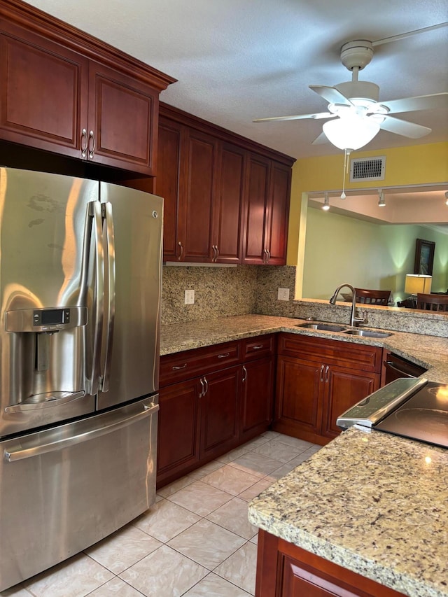 kitchen featuring a sink, visible vents, stainless steel refrigerator with ice dispenser, backsplash, and light stone countertops