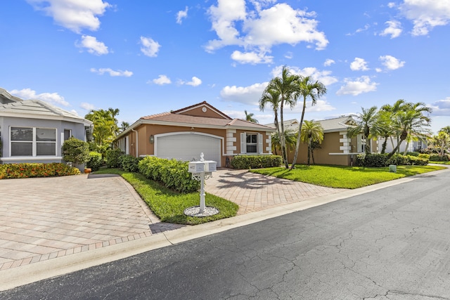 ranch-style home featuring decorative driveway, an attached garage, a front yard, and stucco siding