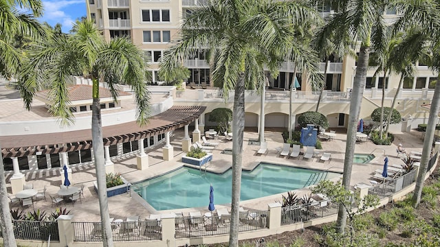 community pool with a hot tub, fence, and a patio