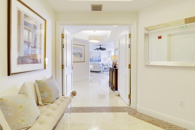 corridor featuring a tray ceiling, visible vents, and baseboards