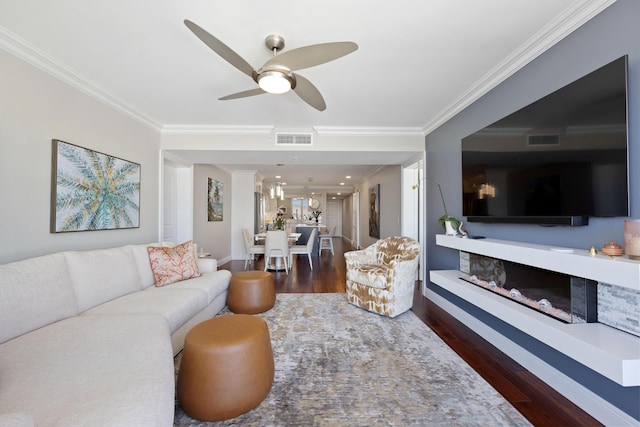 living room with a ceiling fan, wood finished floors, visible vents, and crown molding