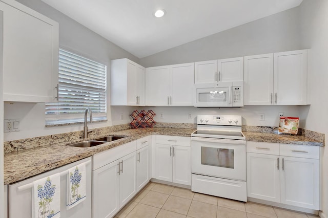 kitchen with white appliances, light tile patterned floors, white cabinets, vaulted ceiling, and a sink