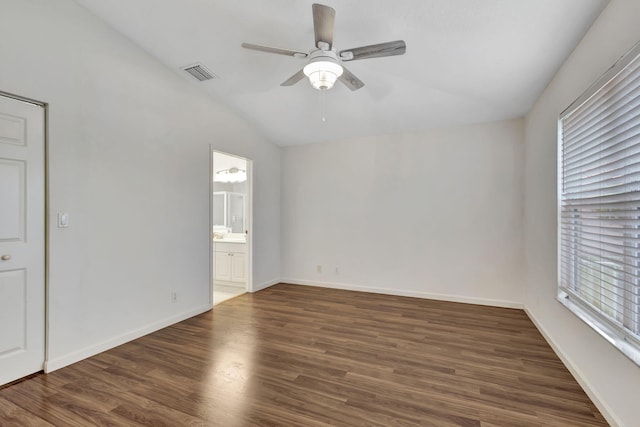 unfurnished bedroom with baseboards, visible vents, dark wood finished floors, lofted ceiling, and ensuite bath