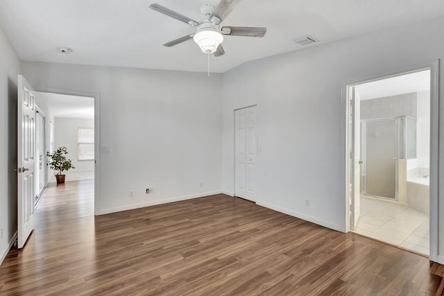 unfurnished bedroom featuring ensuite bath, dark wood finished floors, visible vents, and baseboards