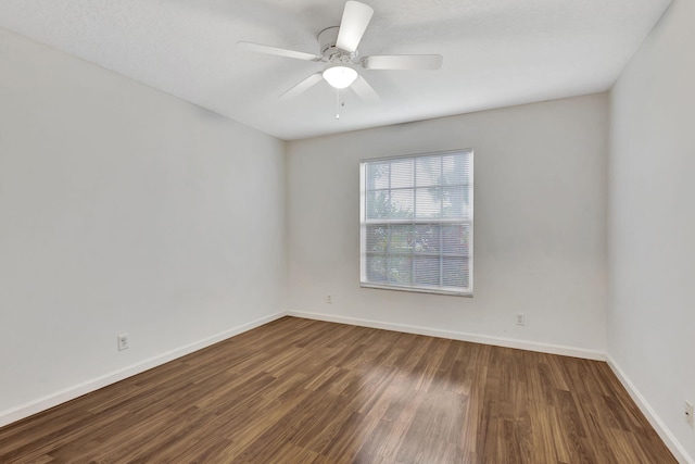 unfurnished room with dark wood-style flooring, ceiling fan, and baseboards