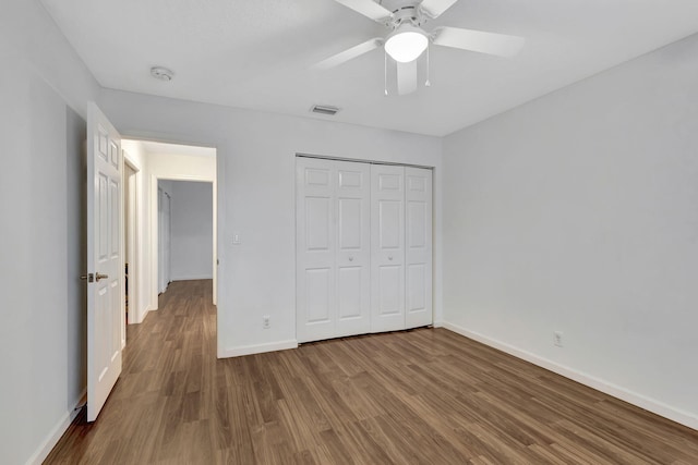 unfurnished bedroom featuring ceiling fan, wood finished floors, visible vents, baseboards, and a closet