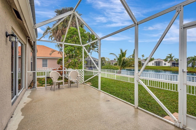 unfurnished sunroom featuring a water view, plenty of natural light, and a residential view