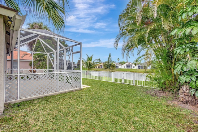 view of yard featuring glass enclosure, a water view, and a fenced backyard