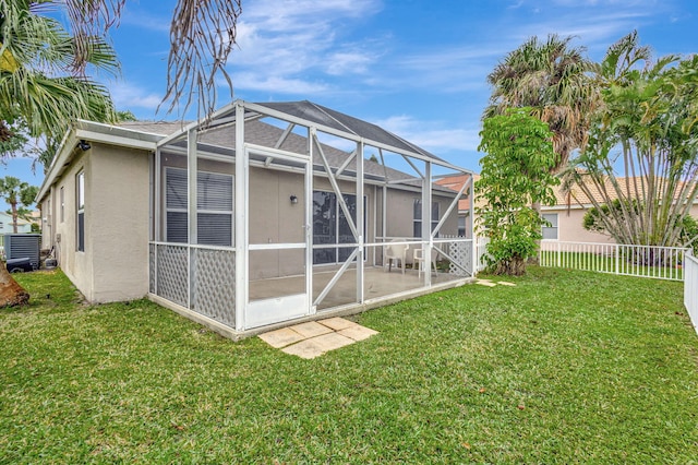 rear view of house featuring glass enclosure, a yard, a fenced backyard, and stucco siding