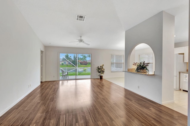 unfurnished living room featuring light wood-style floors, visible vents, ceiling fan, and baseboards