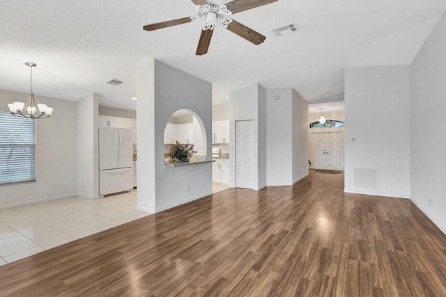 unfurnished living room featuring light wood-type flooring, visible vents, and lofted ceiling