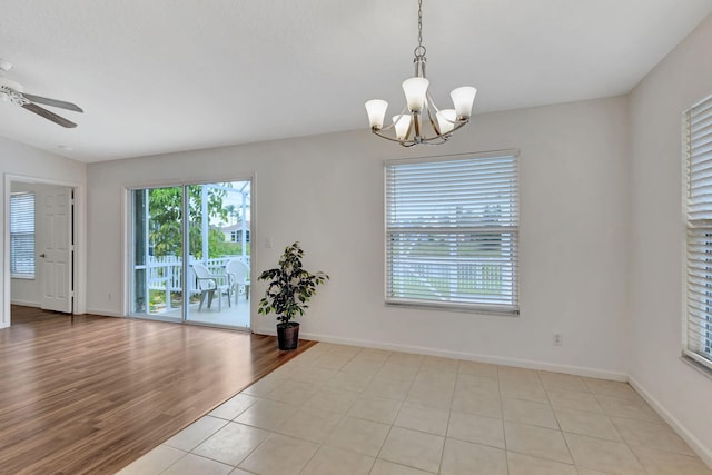 unfurnished room featuring light wood-type flooring, lofted ceiling, baseboards, and ceiling fan with notable chandelier