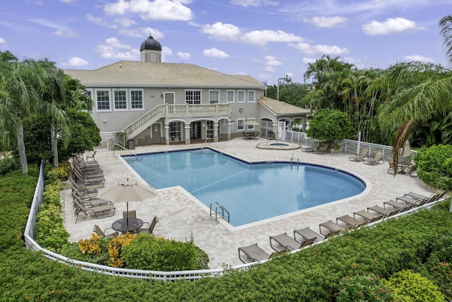 pool with a patio, stairway, fence, and a hot tub