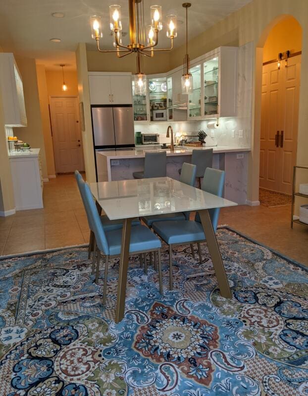 dining space with light tile patterned floors, a notable chandelier, and baseboards