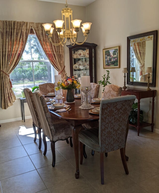 tiled dining area with baseboards and a notable chandelier