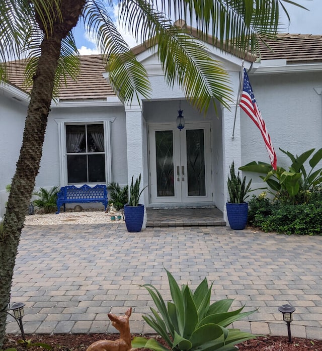 entrance to property featuring french doors, a tile roof, and stucco siding