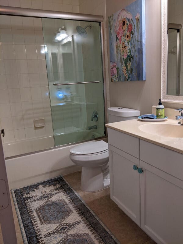 bathroom featuring toilet, shower / bath combination with glass door, vanity, and tile patterned floors