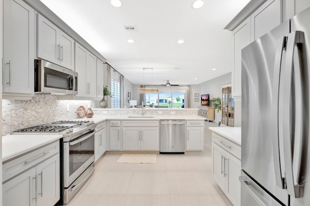 kitchen with light countertops, appliances with stainless steel finishes, a peninsula, and a sink