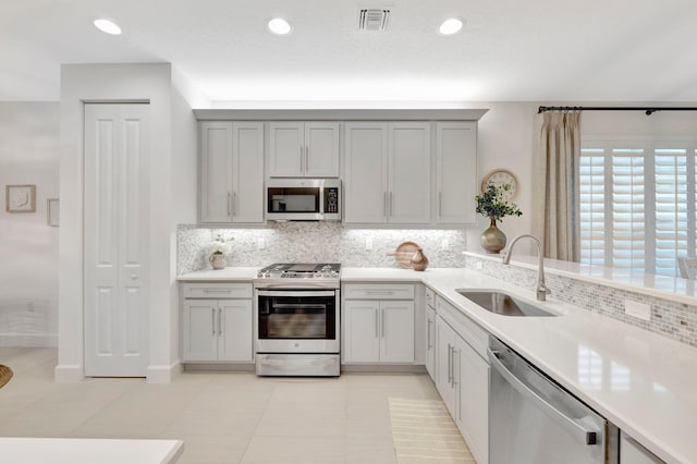 kitchen featuring tasteful backsplash, visible vents, appliances with stainless steel finishes, light countertops, and a sink