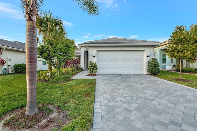 view of front of house featuring an attached garage, a tile roof, decorative driveway, stucco siding, and a front yard