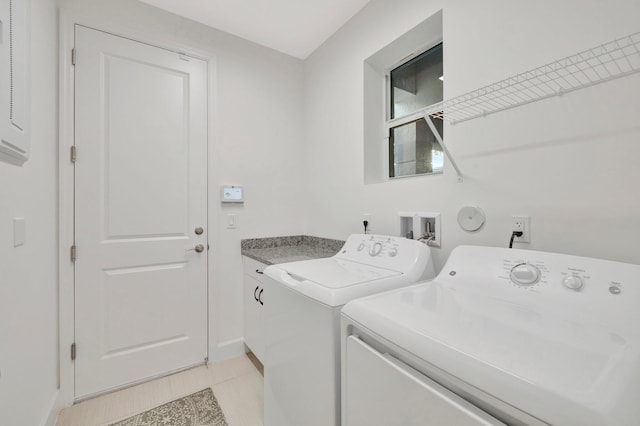 clothes washing area with cabinet space, washer and clothes dryer, baseboards, and light tile patterned floors