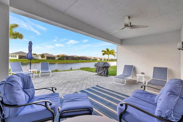 view of patio with ceiling fan, a water view, a grill, and a residential view