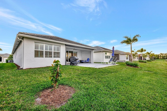 back of property with a patio, a lawn, a ceiling fan, and stucco siding