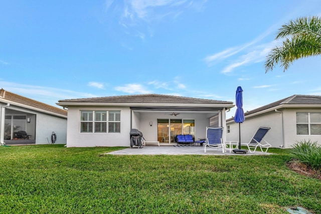 rear view of property with a patio, a yard, a ceiling fan, and stucco siding