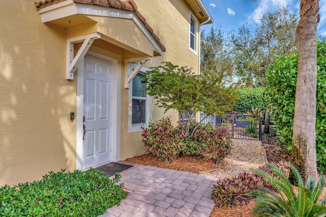 view of exterior entry featuring fence and stucco siding