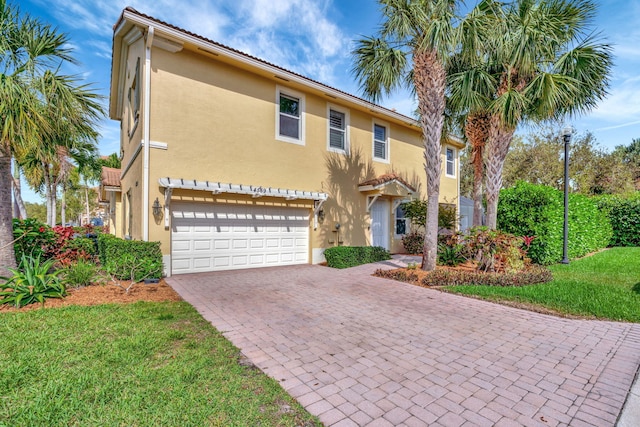 view of front of house featuring a front lawn, decorative driveway, an attached garage, and stucco siding