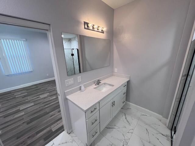 full bathroom featuring marble finish floor, walk in shower, vanity, and baseboards