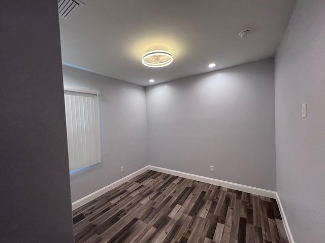 empty room featuring dark wood-style floors, visible vents, baseboards, and recessed lighting