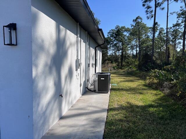 view of property exterior with a yard, central AC unit, and stucco siding