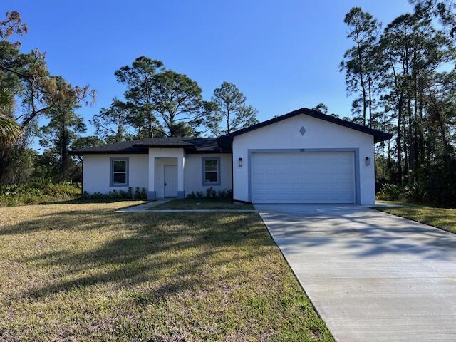 ranch-style house with a front lawn, driveway, an attached garage, and stucco siding