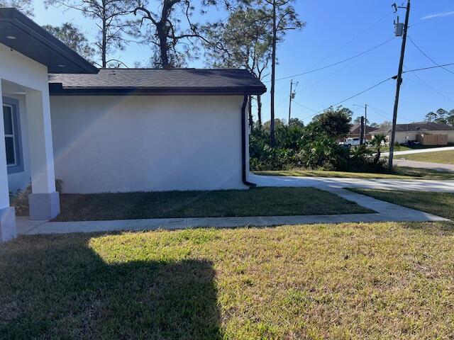 view of side of property featuring a lawn and stucco siding