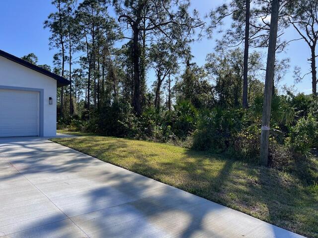 view of yard featuring a garage and concrete driveway