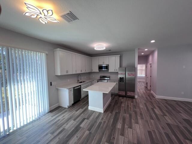 kitchen featuring visible vents, a center island, stainless steel appliances, light countertops, and white cabinetry