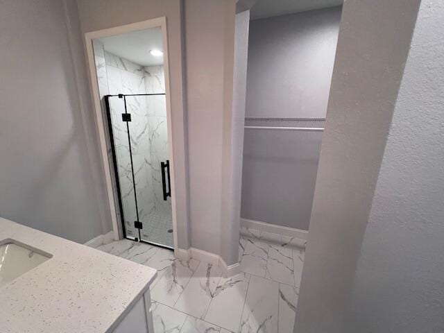 full bath with vanity, baseboards, marble finish floor, a spacious closet, and a marble finish shower