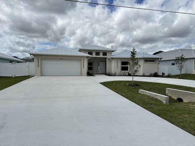 prairie-style home with concrete driveway, a gate, metal roof, fence, and a garage