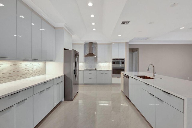 kitchen featuring a sink, visible vents, wall chimney range hood, appliances with stainless steel finishes, and modern cabinets