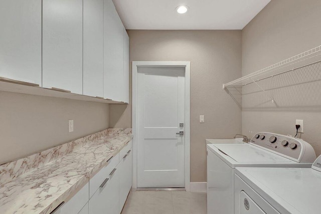 washroom with washer and clothes dryer, light tile patterned floors, cabinet space, a sink, and baseboards