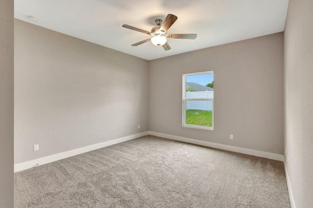 empty room with carpet floors, baseboards, and a ceiling fan